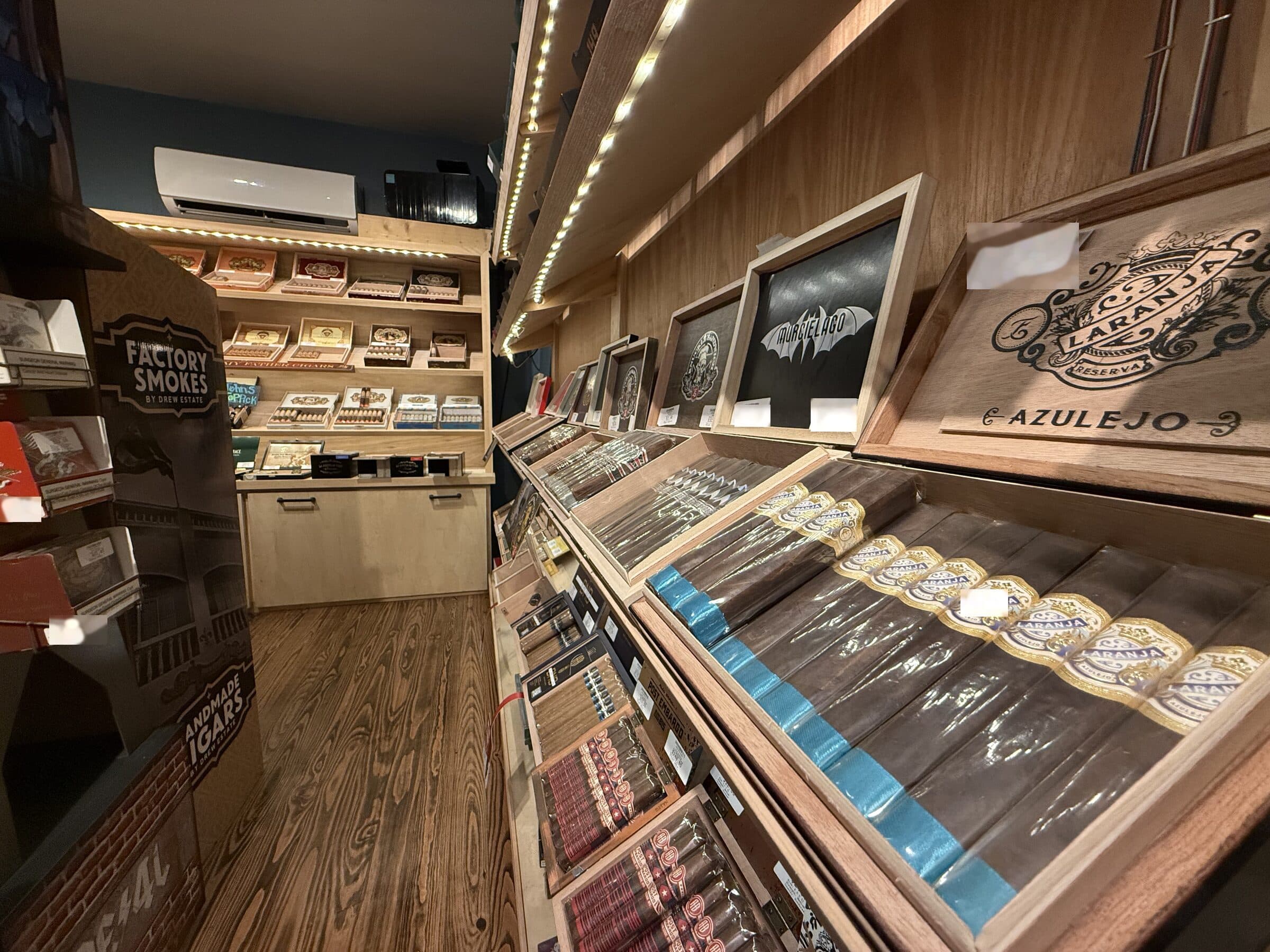 Boxes of Laranja Reserva Azulejo and Murcielago cigars on lit humidor shelves